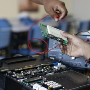 Close up of hands working with electronics equipment and circuit board in a lab setting